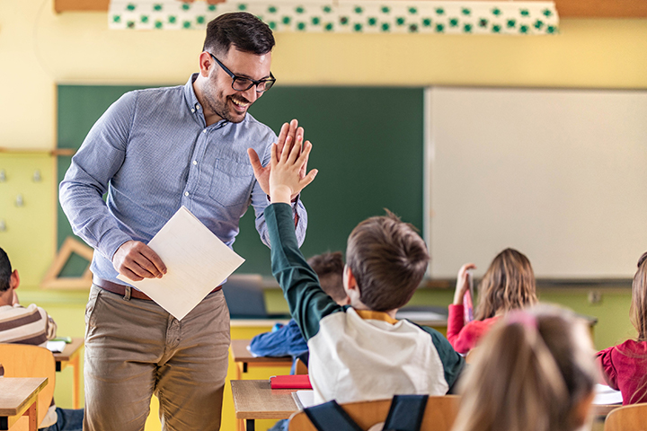 Teacher high-fiving a student in the classroom